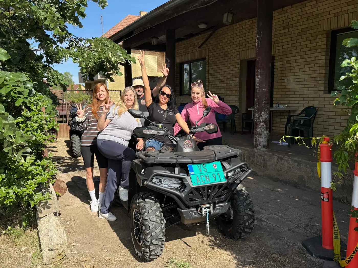 A group of women laughing and celebrating beside a quad bike after a Bela Crkva tour