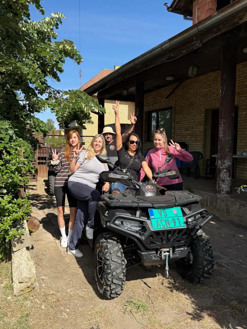 Friends throwing their hands up beside a quad bike on a Mad Max tour in Bela Crkva