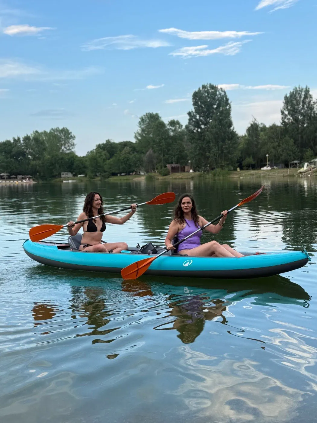 Two friends paddling a kayak across the Bela Crkva lake under a blue summer sky