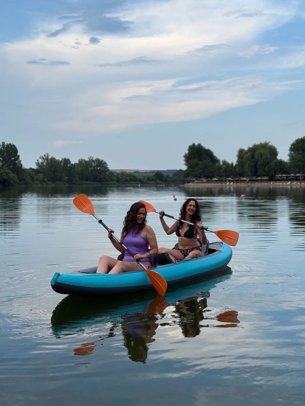 Two friends laughing as they paddle a kayak on the Bela Crkva lake
